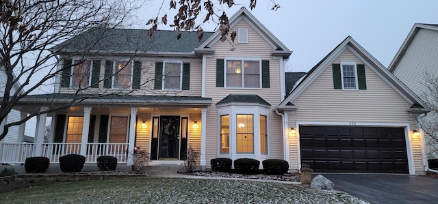 view of front of home featuring a porch, a garage, and a front yard