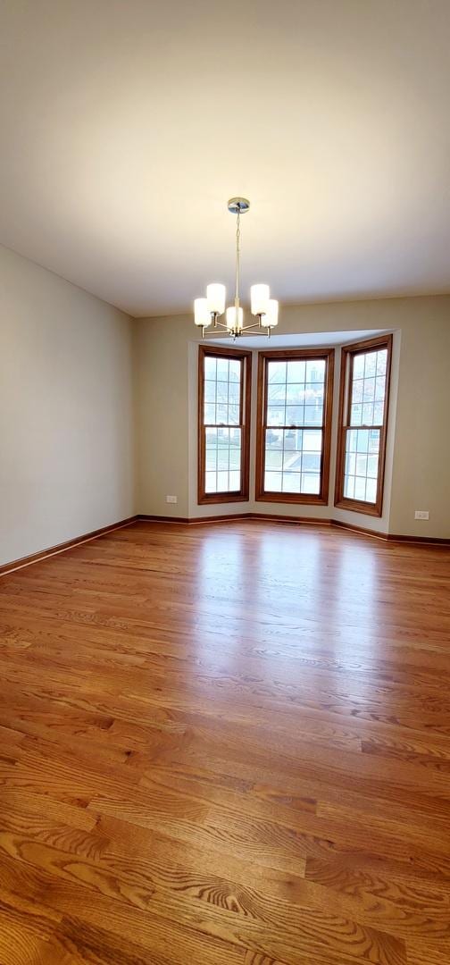 spare room featuring light hardwood / wood-style floors and a chandelier