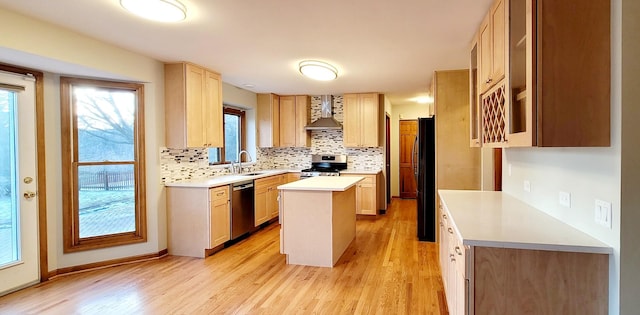 kitchen with wall chimney exhaust hood, a kitchen island, light hardwood / wood-style floors, and appliances with stainless steel finishes