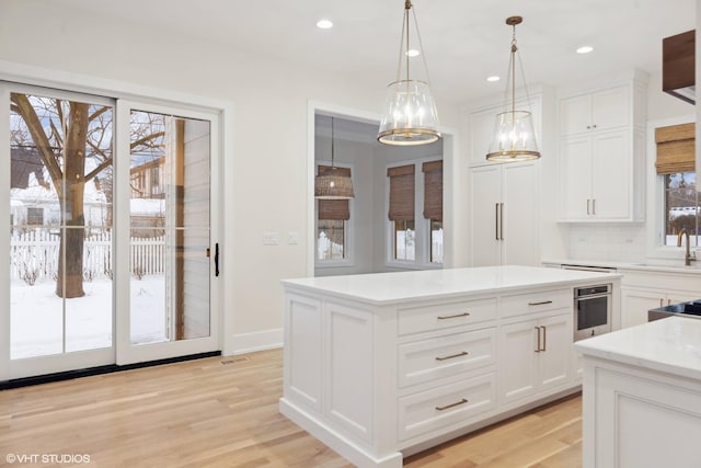 kitchen with backsplash, white cabinetry, hanging light fixtures, and a kitchen island