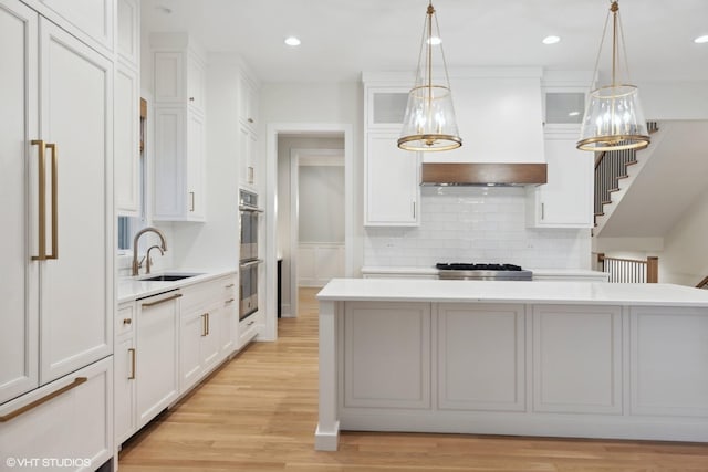 kitchen featuring sink, an inviting chandelier, a center island, white cabinetry, and hanging light fixtures