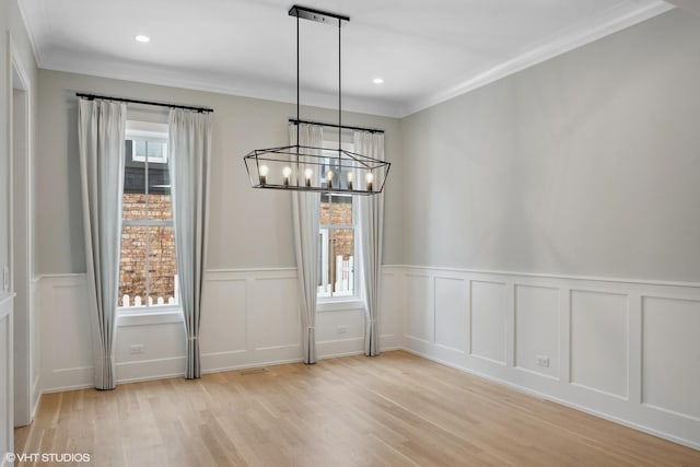 unfurnished dining area with plenty of natural light, ornamental molding, light hardwood / wood-style flooring, and a chandelier