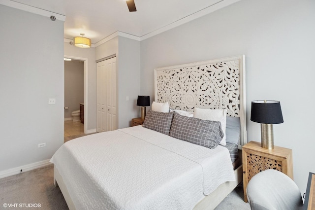 carpeted bedroom with ceiling fan, ornamental molding, and a closet