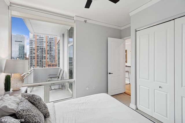 bedroom with ceiling fan, ornamental molding, and a closet