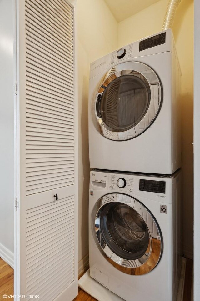 laundry room with wood-type flooring and stacked washer and dryer