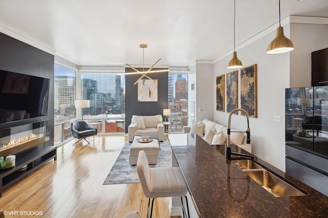 kitchen featuring dark stone countertops, sink, hanging light fixtures, and a wall of windows