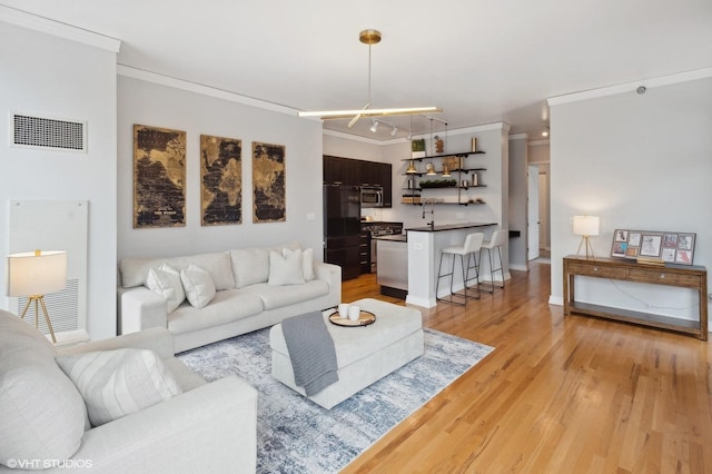 living room featuring light hardwood / wood-style floors, ornamental molding, and an inviting chandelier