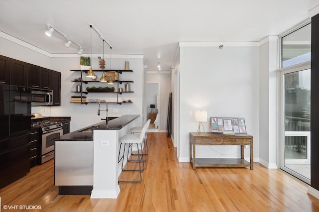 kitchen featuring appliances with stainless steel finishes, track lighting, sink, a kitchen island, and a breakfast bar area