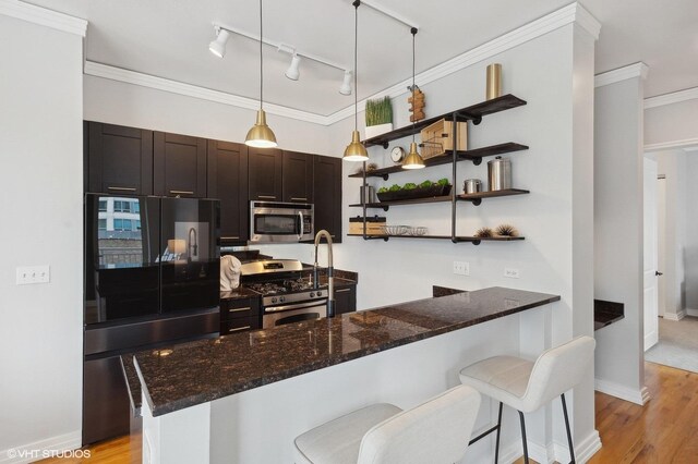 kitchen with rail lighting, a kitchen bar, dark brown cabinetry, and stainless steel appliances