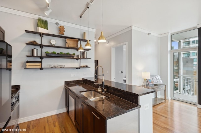 kitchen featuring sink, hanging light fixtures, kitchen peninsula, dark stone countertops, and light hardwood / wood-style floors