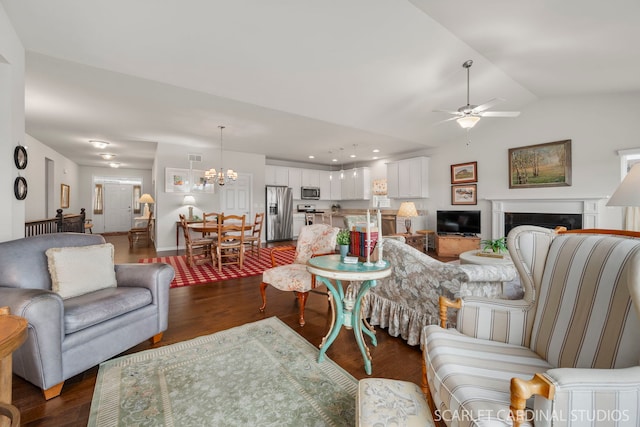 living room featuring ceiling fan with notable chandelier, dark hardwood / wood-style flooring, and vaulted ceiling