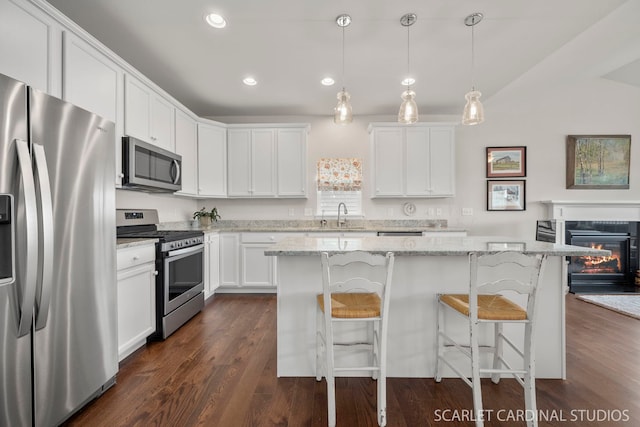 kitchen featuring white cabinets, stainless steel appliances, a kitchen island, and hanging light fixtures