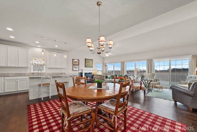 dining space featuring a notable chandelier, lofted ceiling, sink, and dark wood-type flooring