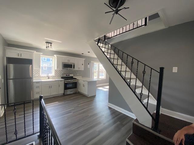 kitchen with white cabinets, stainless steel appliances, tasteful backsplash, and dark hardwood / wood-style floors