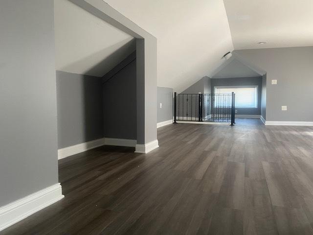 bonus room featuring dark wood-type flooring and vaulted ceiling