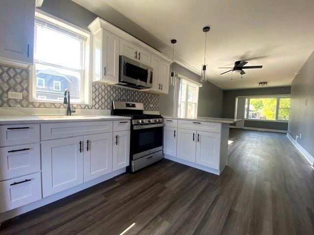 kitchen with tasteful backsplash, stainless steel appliances, sink, pendant lighting, and white cabinetry