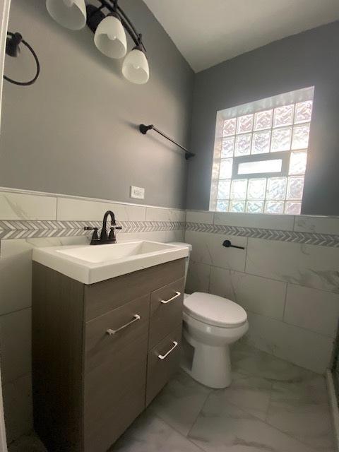 bathroom with vanity, toilet, and tile walls