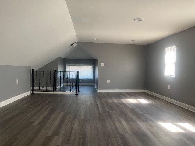 bonus room with dark wood-type flooring and vaulted ceiling