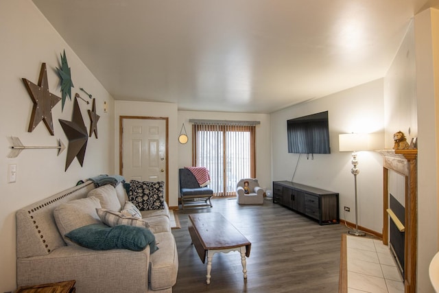 living room with a tile fireplace and hardwood / wood-style floors