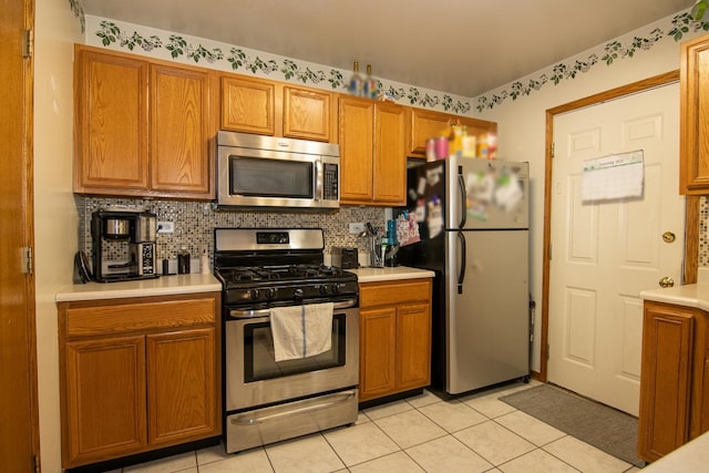 kitchen with appliances with stainless steel finishes, backsplash, and light tile patterned floors