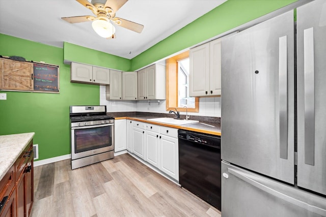 kitchen featuring light wood-type flooring, decorative backsplash, stainless steel appliances, a ceiling fan, and a sink