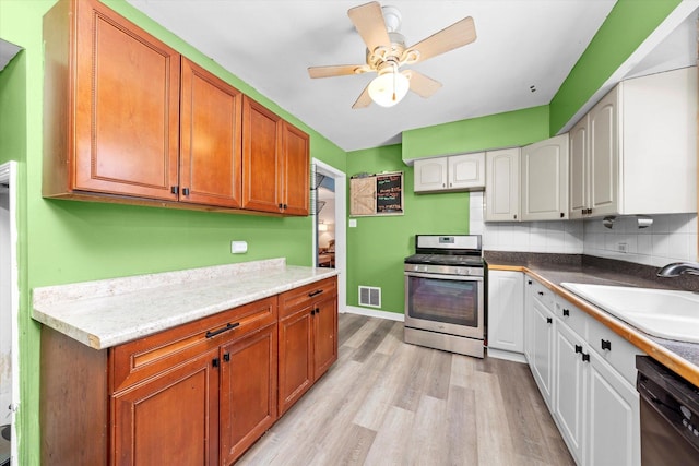 kitchen featuring visible vents, light wood-style flooring, a sink, black dishwasher, and gas range