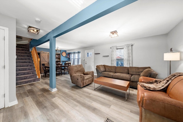 living room featuring stairway, baseboards, and light wood finished floors