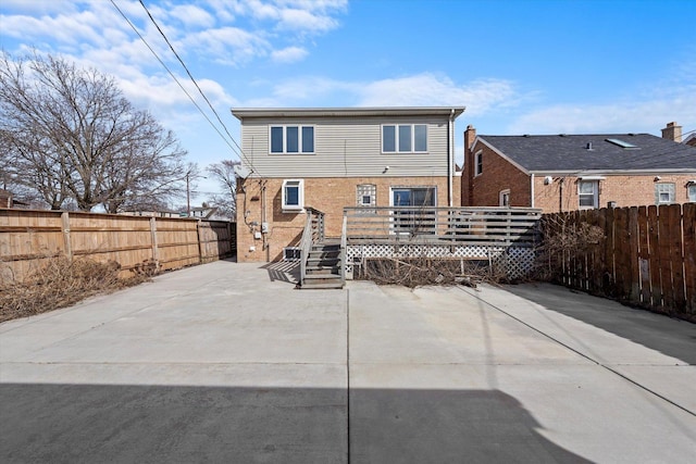 rear view of house featuring a fenced backyard, a deck, brick siding, and a patio