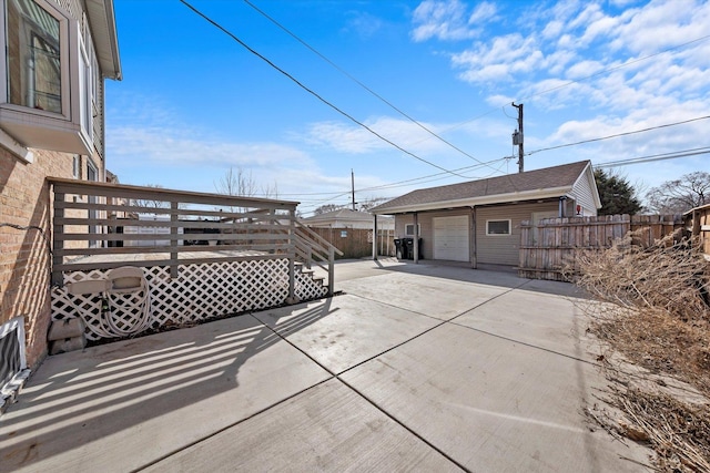 view of patio / terrace featuring a deck, an outbuilding, fence, and a detached garage