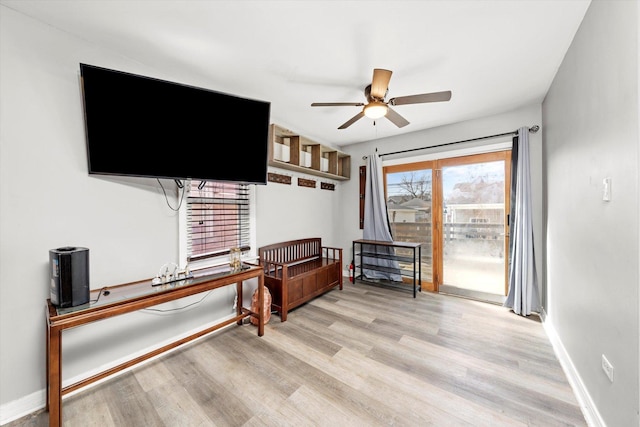 living area with baseboards, ceiling fan, and light wood finished floors