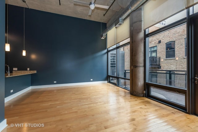 spare room with light wood-type flooring, ceiling fan, and a high ceiling