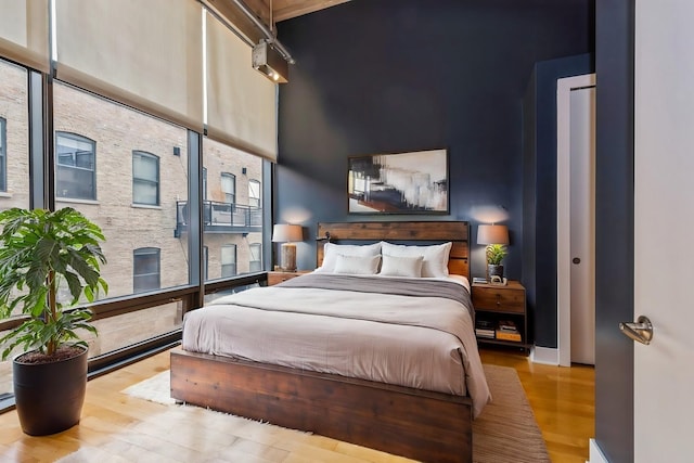 bedroom featuring a towering ceiling and light hardwood / wood-style flooring