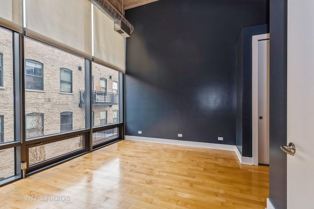 unfurnished room featuring wood-type flooring and a towering ceiling