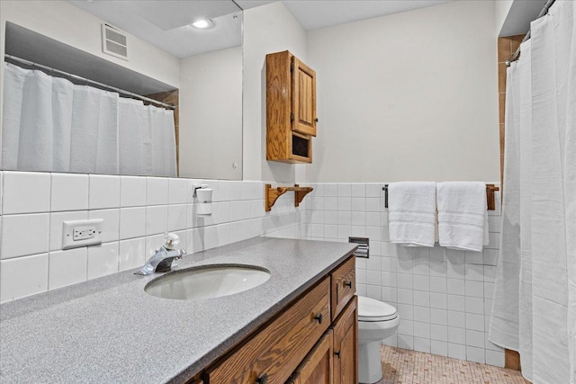 bathroom with tile patterned floors, vanity, tile walls, and toilet