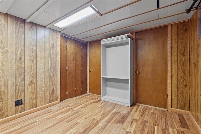 basement featuring light wood-type flooring and wooden walls