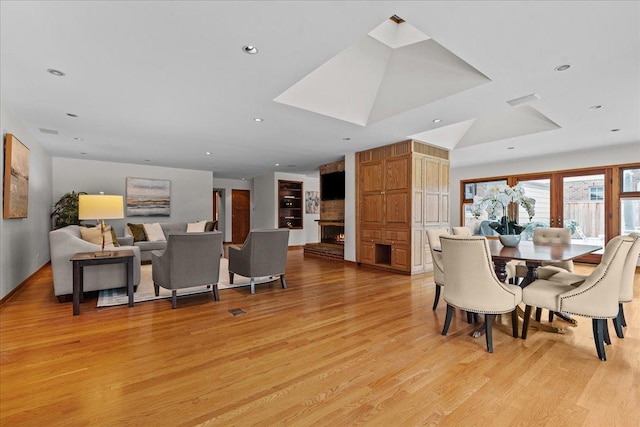 dining room with a large fireplace and light hardwood / wood-style flooring