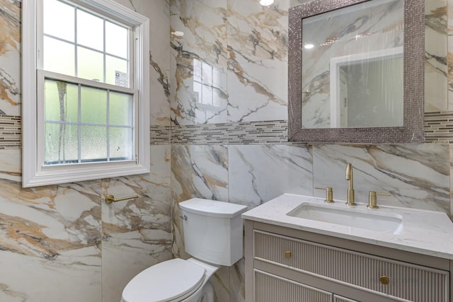 bathroom with vanity, toilet, and tile walls