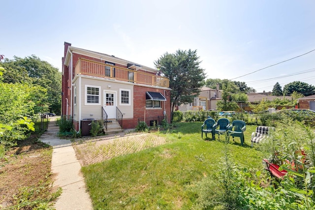 back of property with a yard, central air condition unit, and a balcony