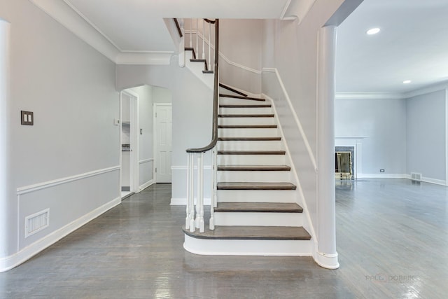 stairs with wood-type flooring and crown molding