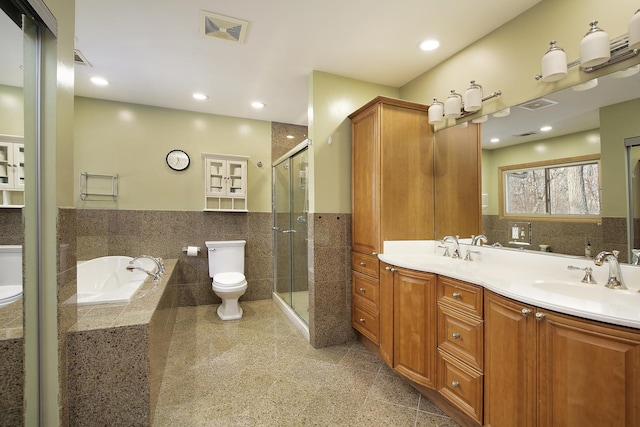 full bathroom with tile walls, toilet, vanity, and shower with separate bathtub