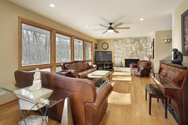 living room with ceiling fan, a fireplace, and light hardwood / wood-style floors