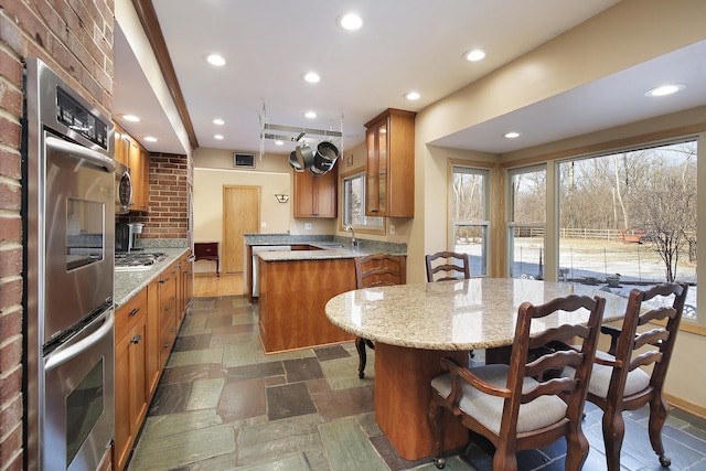 kitchen with light stone counters, sink, appliances with stainless steel finishes, and a center island