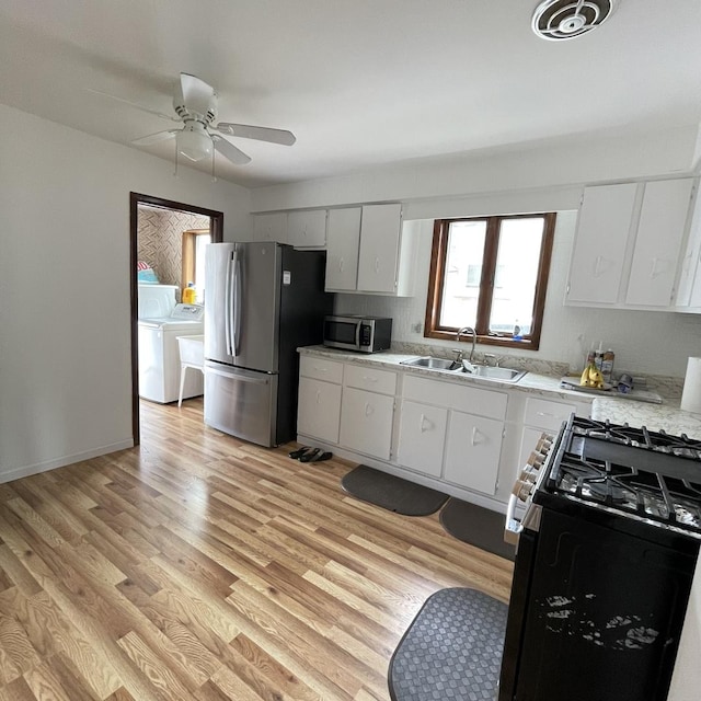 kitchen with white cabinetry, sink, stainless steel appliances, independent washer and dryer, and light wood-type flooring