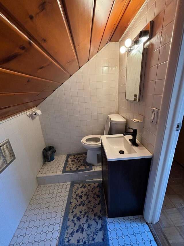 bathroom with vanity, toilet, and tile walls