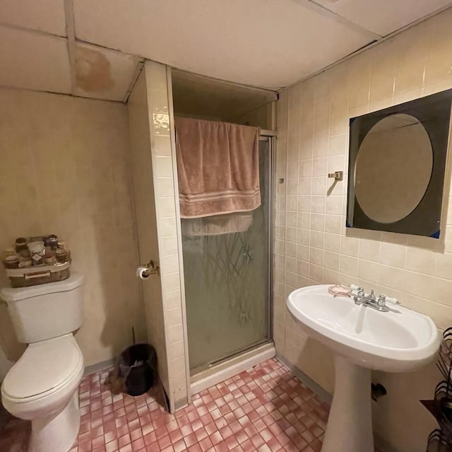 bathroom featuring tile walls, an enclosed shower, and toilet