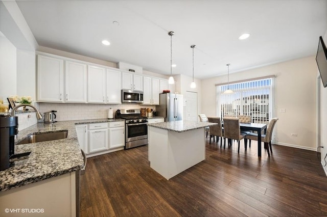 kitchen with white cabinets, sink, hanging light fixtures, a kitchen island, and stainless steel appliances