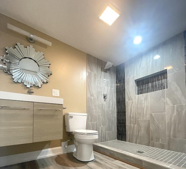 bathroom featuring wood-type flooring, a tile shower, and toilet