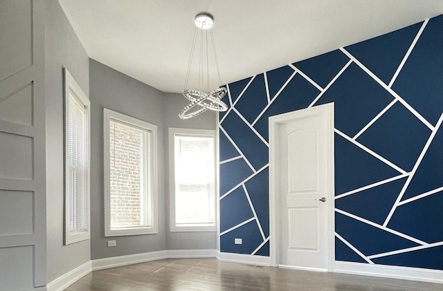 empty room featuring a chandelier and wood-type flooring