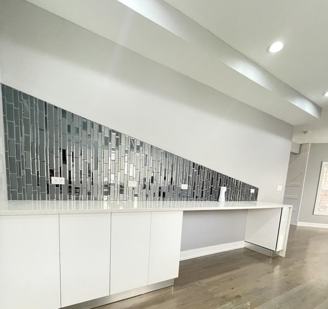 interior space featuring white cabinets, decorative backsplash, dark hardwood / wood-style flooring, and kitchen peninsula