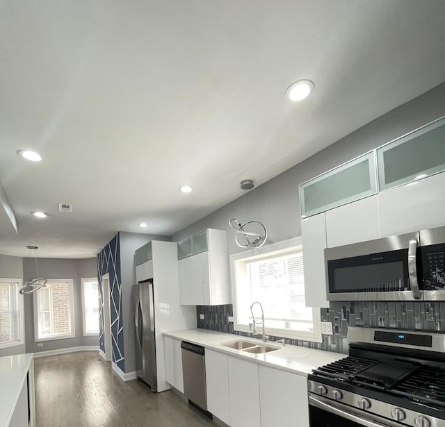 kitchen with an inviting chandelier, white cabinets, sink, decorative light fixtures, and stainless steel appliances